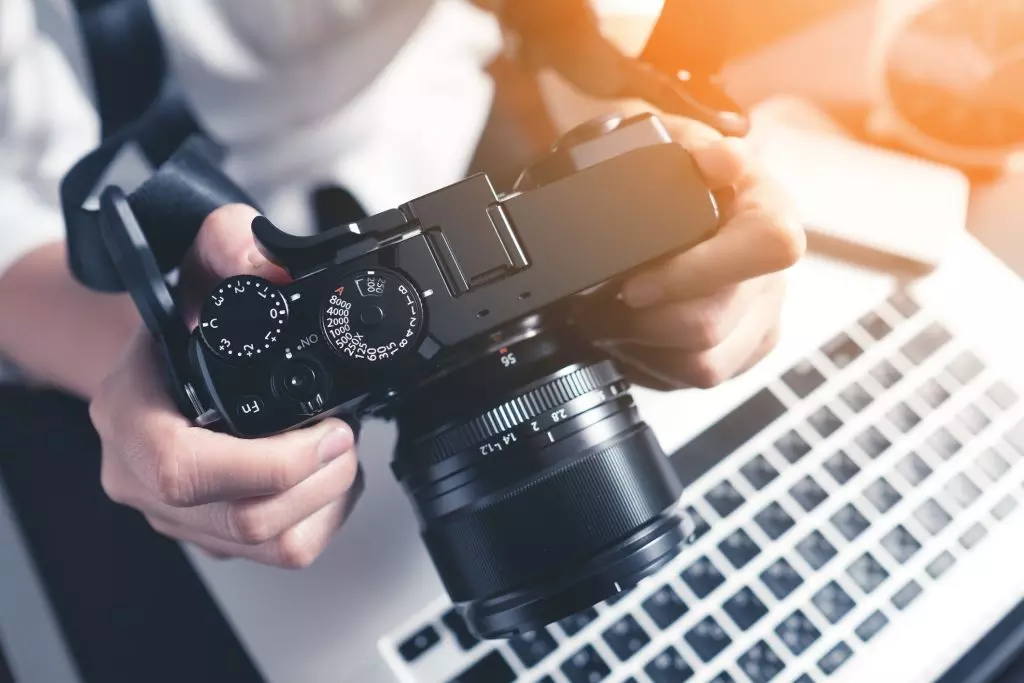 fotograf siedzący przy biurku z aparatem w dłoni